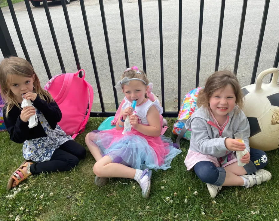 a group of girls sitting on the grass eating ice cream