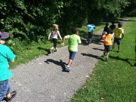 a group of children running on a path in a park