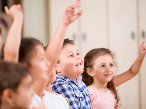 a group of children raising their hands