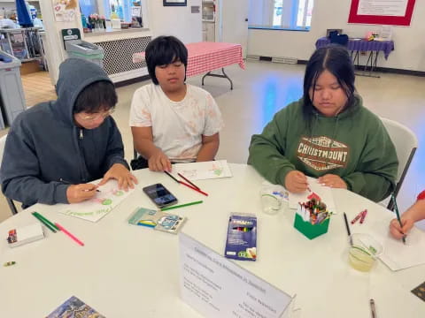 a group of people sitting at a table with cards and pens