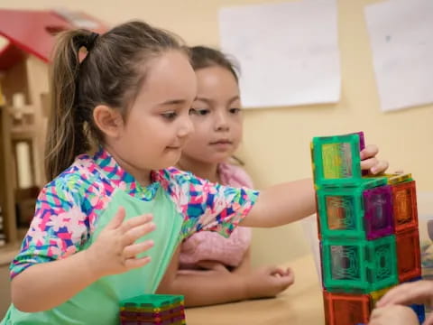 a couple of young girls playing with toys on a table