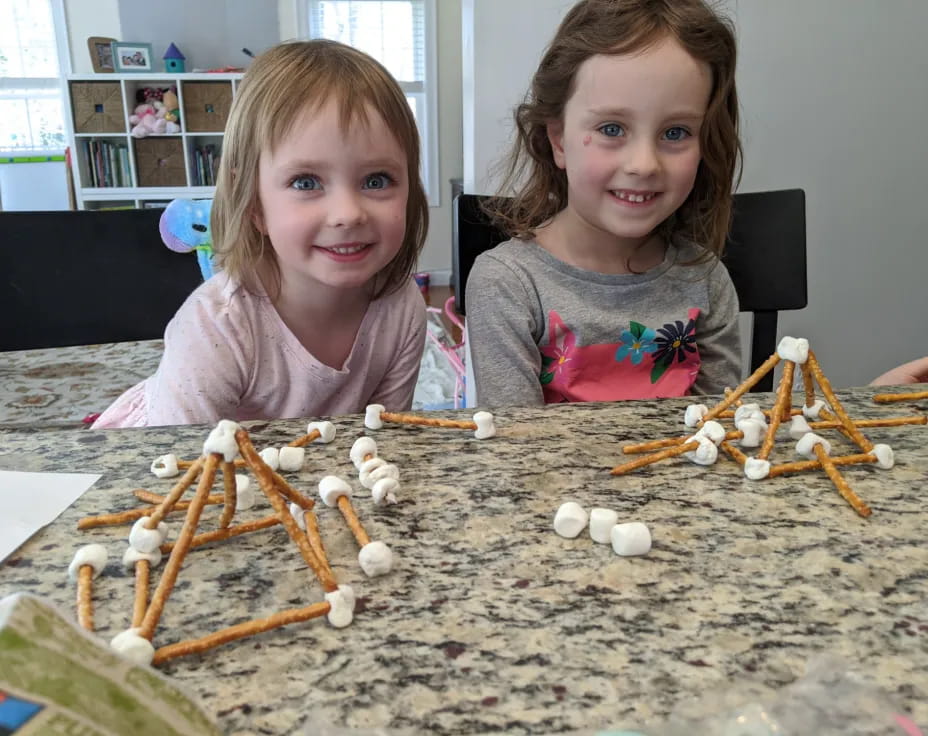 two girls sitting at a table with toys