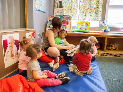 a group of children sitting on a mat in a room