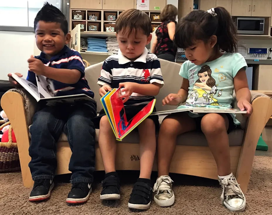 a group of children sitting on a bench reading books