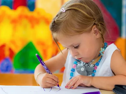 a young girl writing on a piece of paper