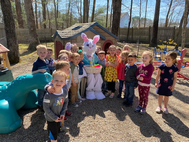 a group of children posing with a person in a rabbit garment