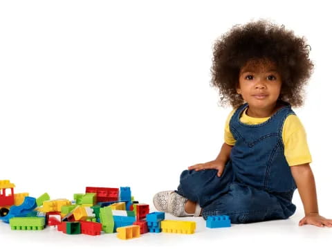 a baby sitting on the floor with a pile of colorful blocks