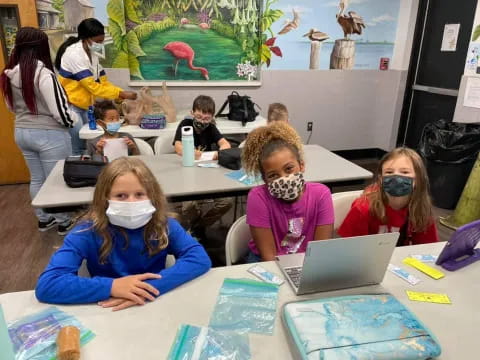 a group of children sitting at a table with a laptop