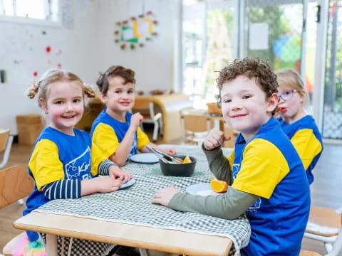 a group of kids sitting at a table eating