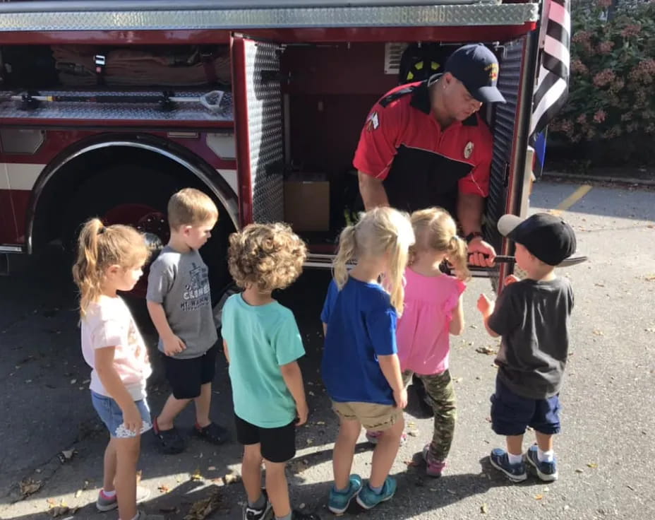 a group of children standing in front of a firetruck