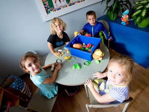 a group of kids sitting around a table with toys