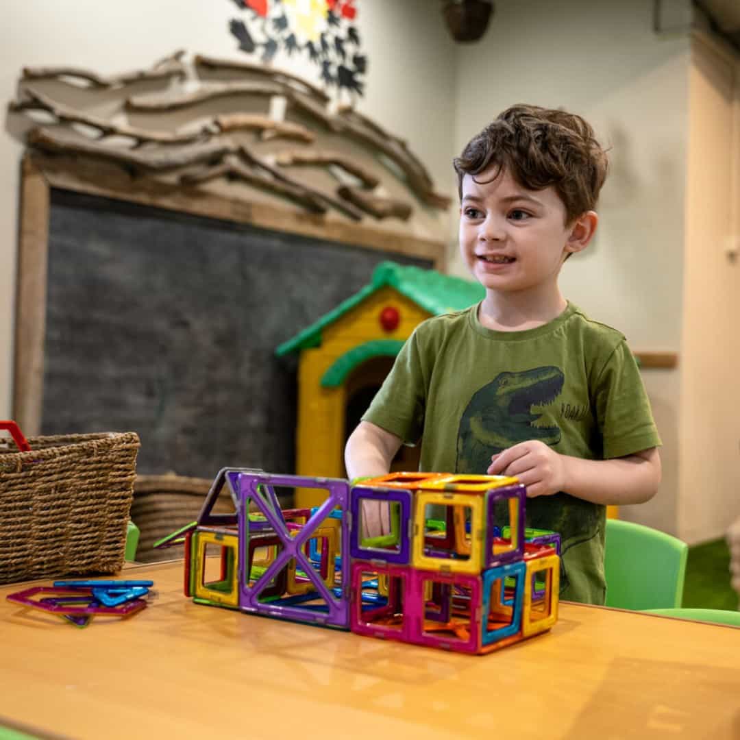 a boy sitting at a table with a toy train