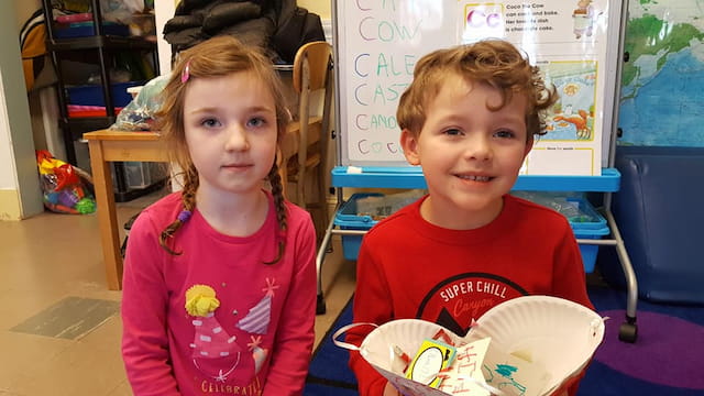 a couple of children sitting at a table with food