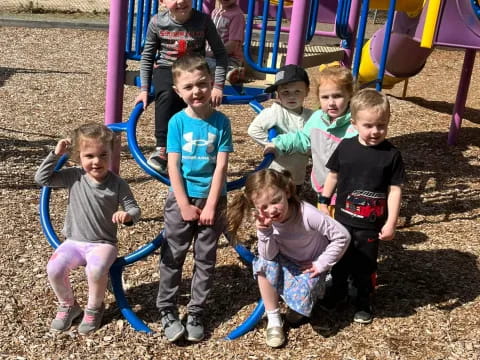a group of children posing for a photo in front of a playground
