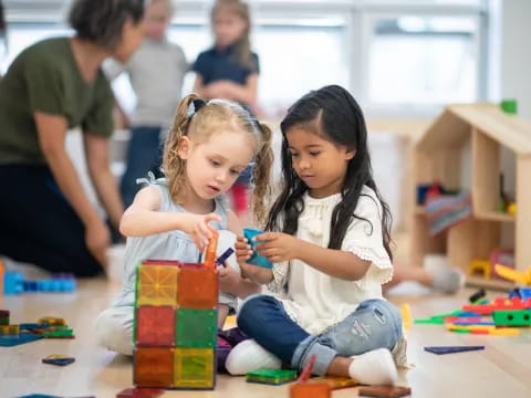 a couple of young girls playing with toys on the floor