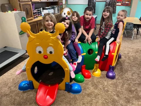 a group of children sitting on a toy in a room