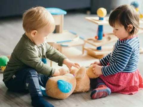 a couple of children playing with a stuffed animal