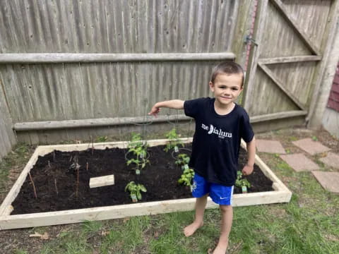 a boy standing in front of a garden