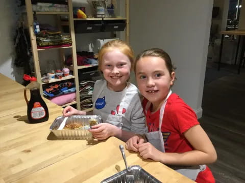 a couple of girls sitting at a table with a cake