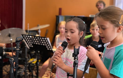 a group of kids singing into microphones