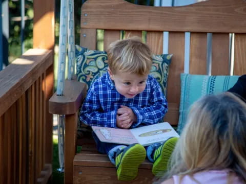 a boy sitting on a bench reading a book