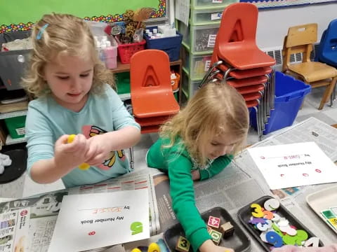 a couple of young girls playing with toys in a classroom