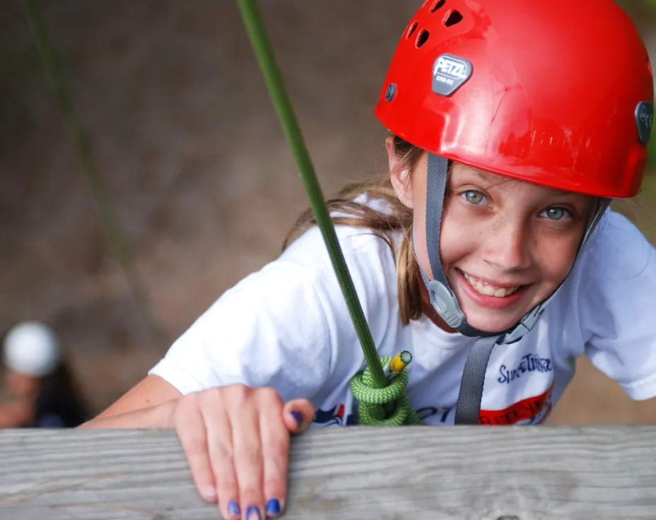 a young girl wearing a helmet and holding a green plant