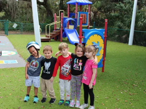 a group of children posing for a photo in front of a playground