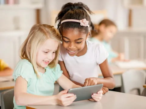 a young girl and a young girl looking at a tablet