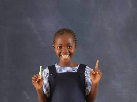 a young girl holding a pencil and smiling