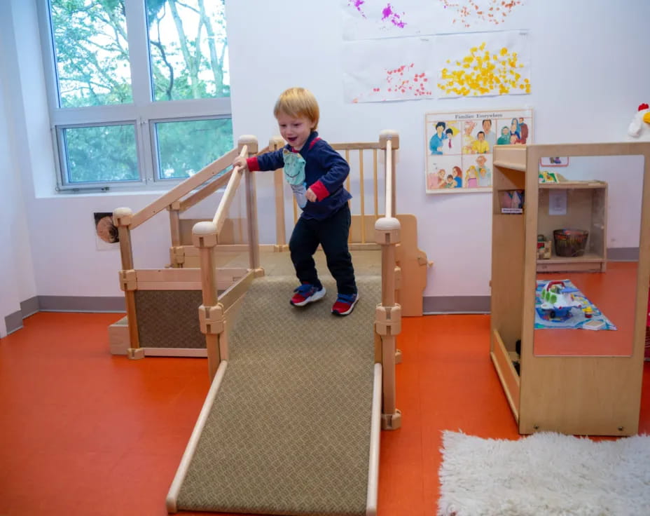 a child on a slide in a room with a window and a wood frame