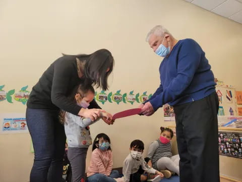 a woman and a man with a child in a room with children