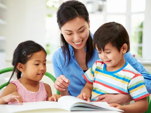 a person and two children looking at a book