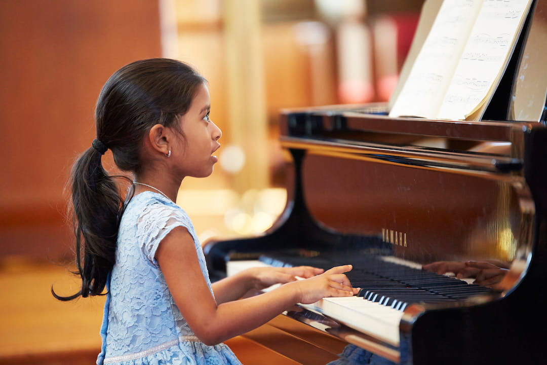 a young girl playing a piano