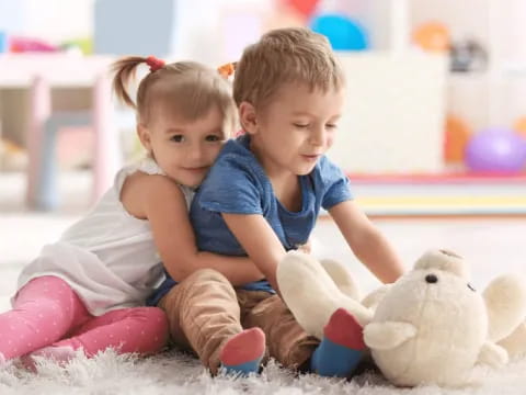 a couple of children sitting on the floor with a stuffed animal