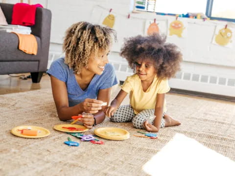 a person and a child playing with toys on the floor