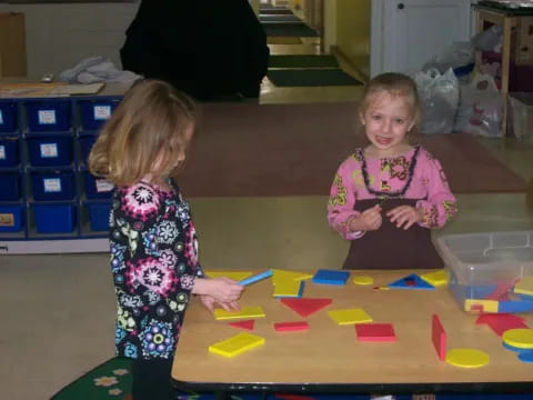 a couple of young girls playing with colorful blocks on the floor