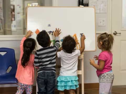 a group of children writing on a whiteboard