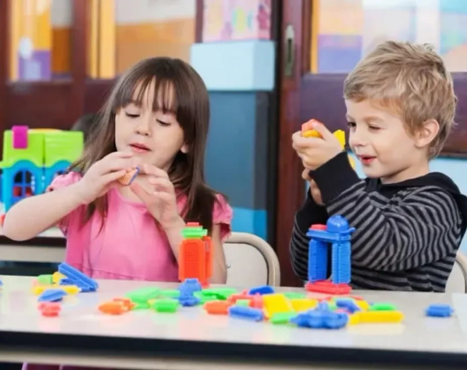 a boy and girl sitting at a table with toys