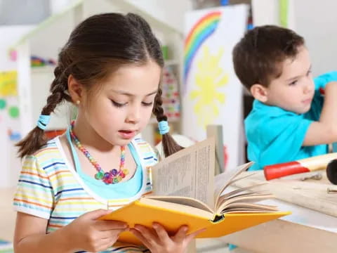 a young girl and a young boy reading a book