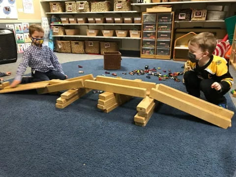 a couple of boys playing with wooden blocks in a library