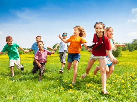 a group of children running in a grassy field