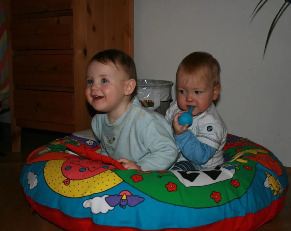 a couple of babies sit on a bed
