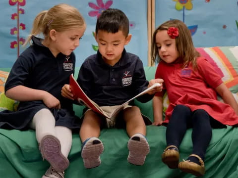 a group of children sitting on a couch reading a book