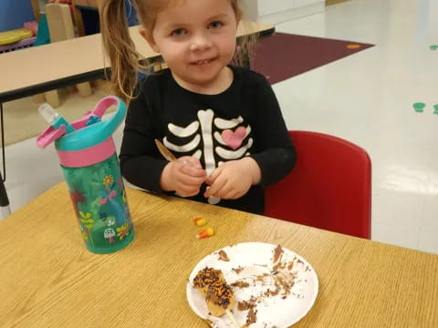 a girl sitting at a table with a plate of food