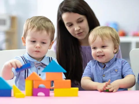 a person and two children playing with blocks