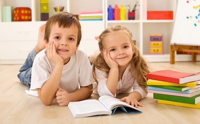 a couple of children sitting on the floor and looking at a book