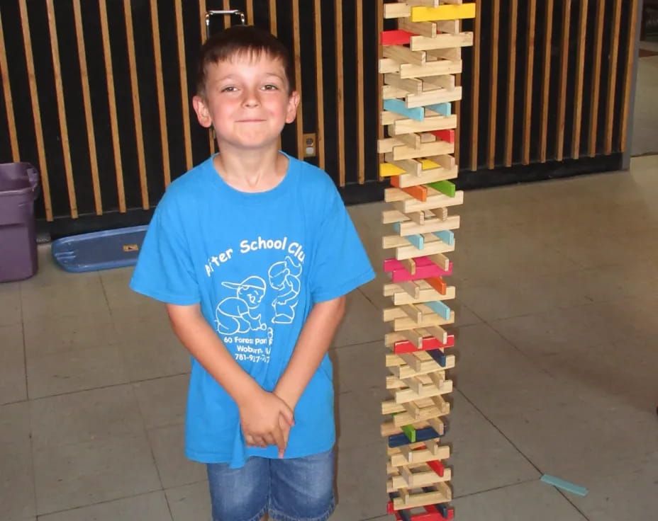 a boy standing in front of a stack of colorful blocks