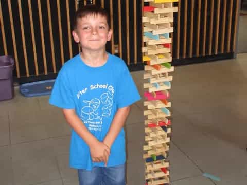 a boy standing in front of a stack of colorful blocks