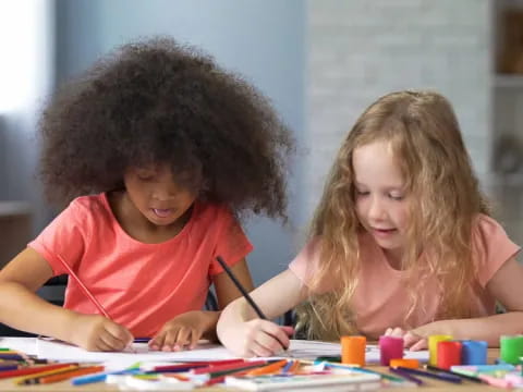 a young girl and a young boy coloring on a table